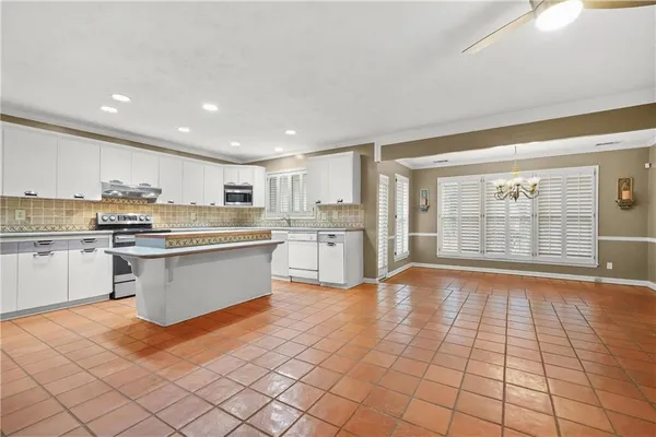 a large kitchen with stainless steel appliances lots of white cabinets