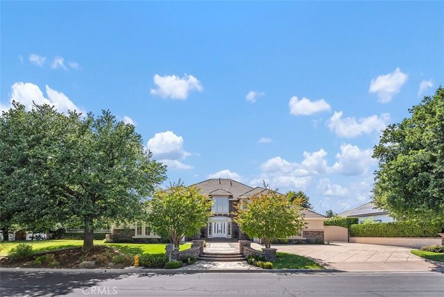 a front view of a house with a yard and a large tree