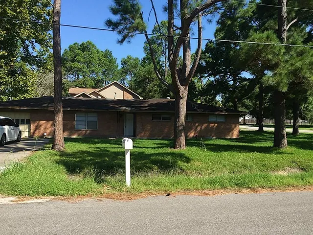 a front view of house with a garden and trees
