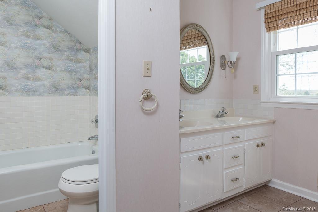 4401 Wolf Pond Road Monroe, NC 28112 - Photo 22 of 24 a bathroom with a toilet a sink a mirror and a bathtub