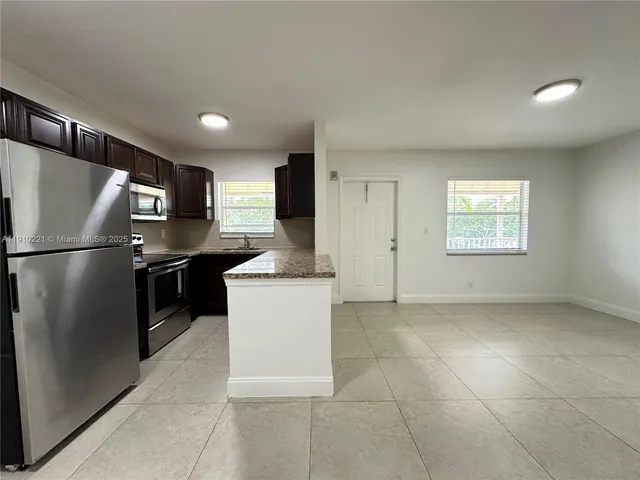 a kitchen with stainless steel appliances granite countertop a refrigerator a sink a stove a microwave and island