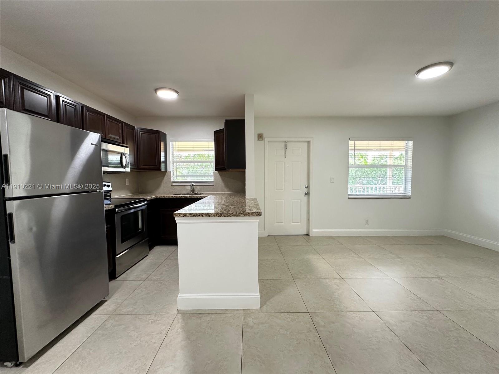 2640 Northeast 8th Avenue, Unit 13 Wilton Manors, FL 33334 - Photo 11 of 34 a kitchen with stainless steel appliances granite countertop a refrigerator a sink a stove a microwave and island