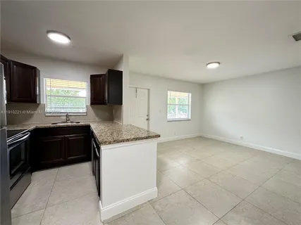 a kitchen with granite countertop a stove a sink and a refrigerator