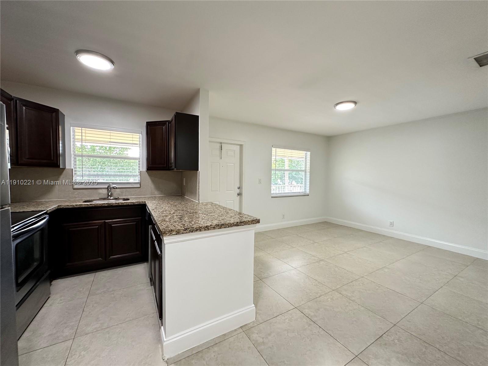 2640 Northeast 8th Avenue, Unit 13 Wilton Manors, FL 33334 - Photo 13 of 34 a kitchen with granite countertop a stove a sink and a refrigerator