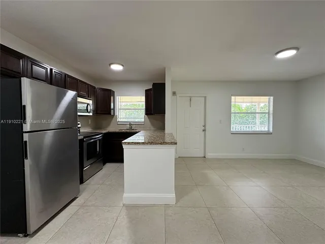 a kitchen with stainless steel appliances granite countertop a refrigerator a sink a stove and a refrigerator