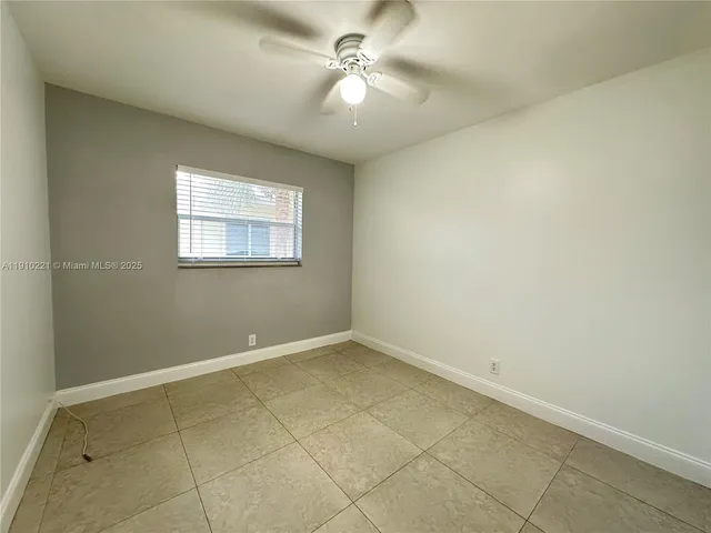 an empty room with a chandelier fan and windows