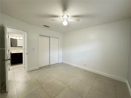 an empty room with closet and a ceiling fan