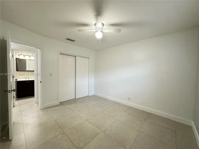 an empty room with closet and a ceiling fan