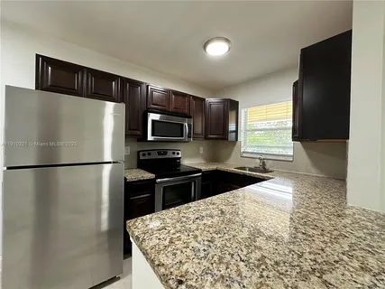 a kitchen with a refrigerator and a stove top oven