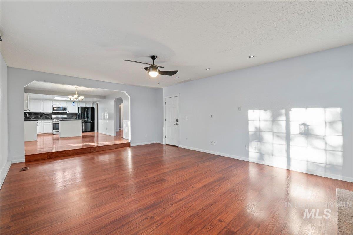 11457 Alejandro Street Boise, ID 83709 - Photo 12 of 42 Unfurnished living room with arched walkways, suspended lighting, dark wood-style flooring, and ceiling fan