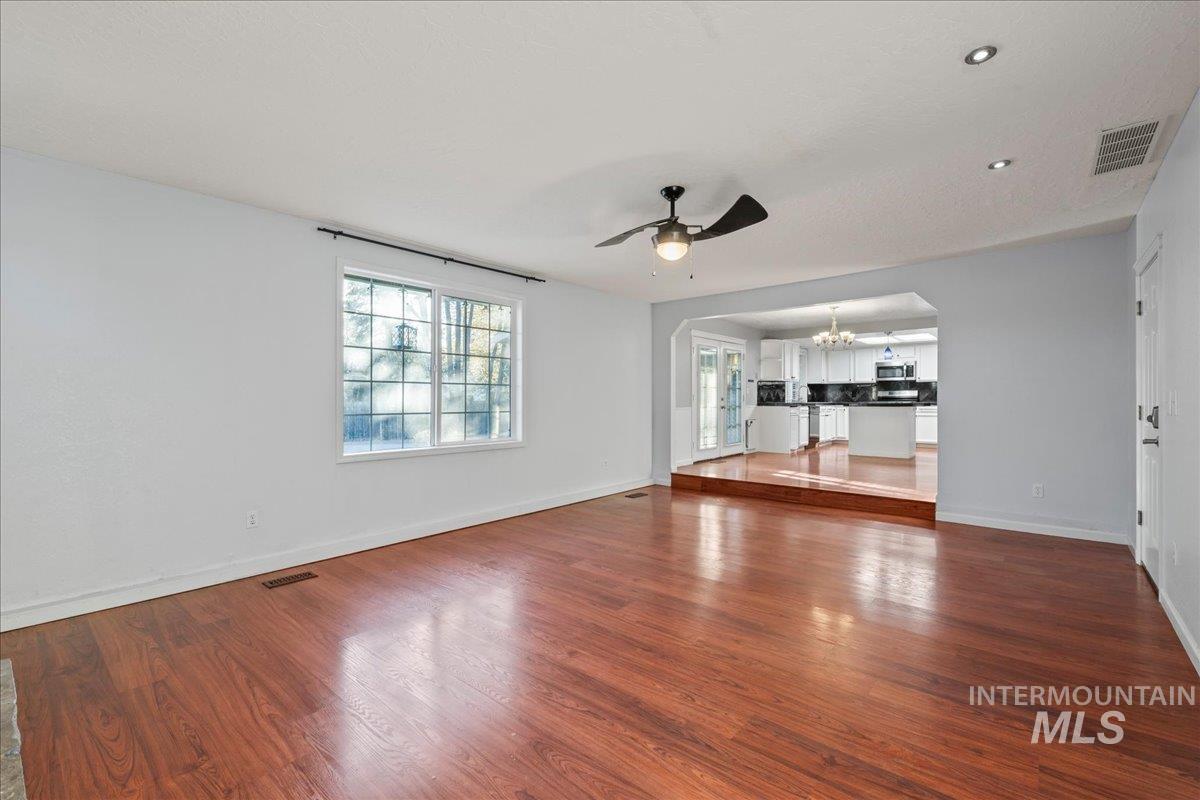 11457 Alejandro Street Boise, ID 83709 - Photo 13 of 42 Unfurnished living room with arched walkways, dark wood-type flooring, ceiling fan, and a chandelier