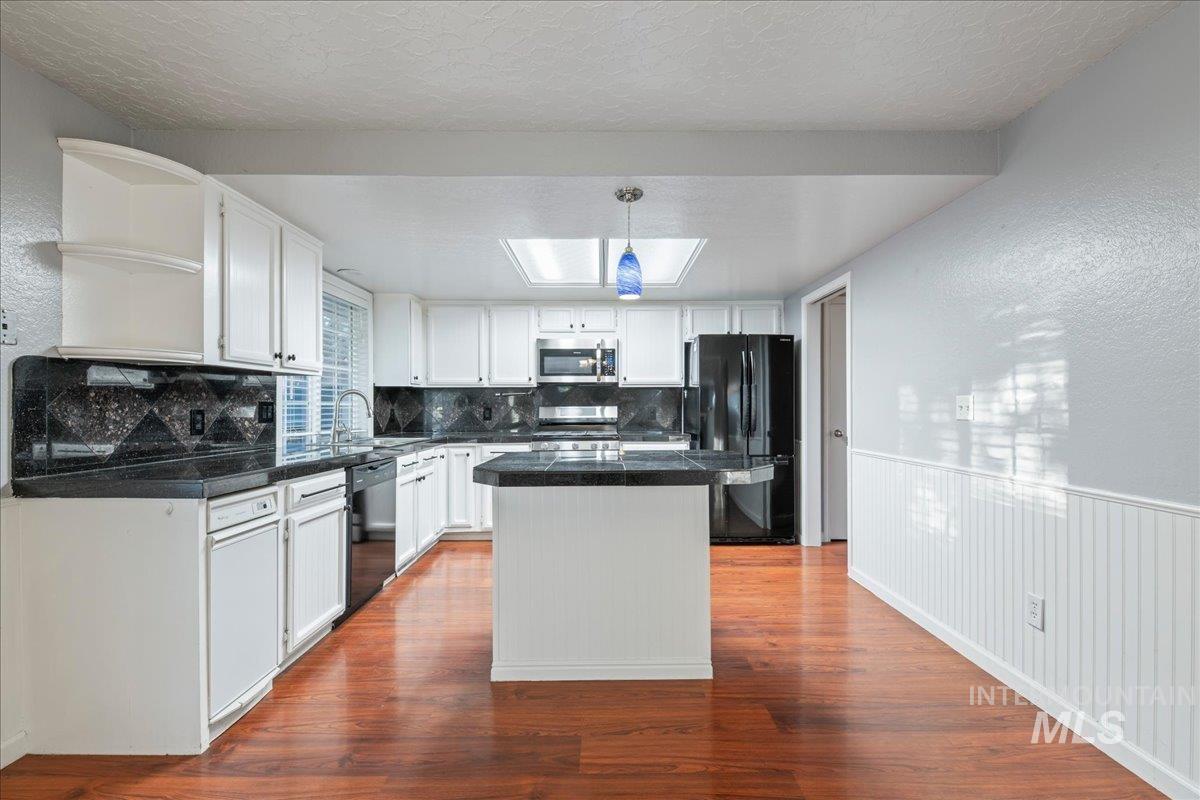 11457 Alejandro Street Boise, ID 83709 - Photo 14 of 42 Kitchen featuring tile counters, backsplash, a kitchen island, wainscoting, and open shelves
