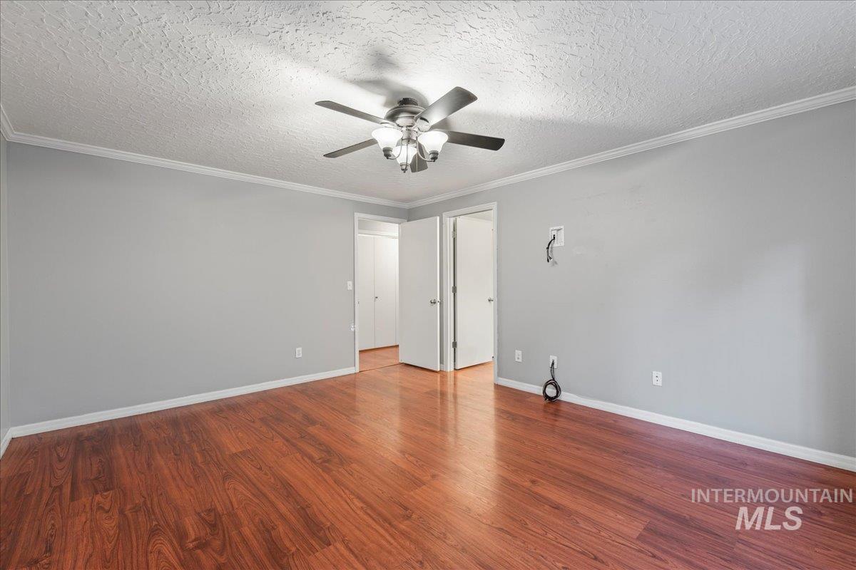11457 Alejandro Street Boise, ID 83709 - Photo 16 of 42 Spare room featuring a textured ceiling, wood finished floors, crown molding, and ceiling fan