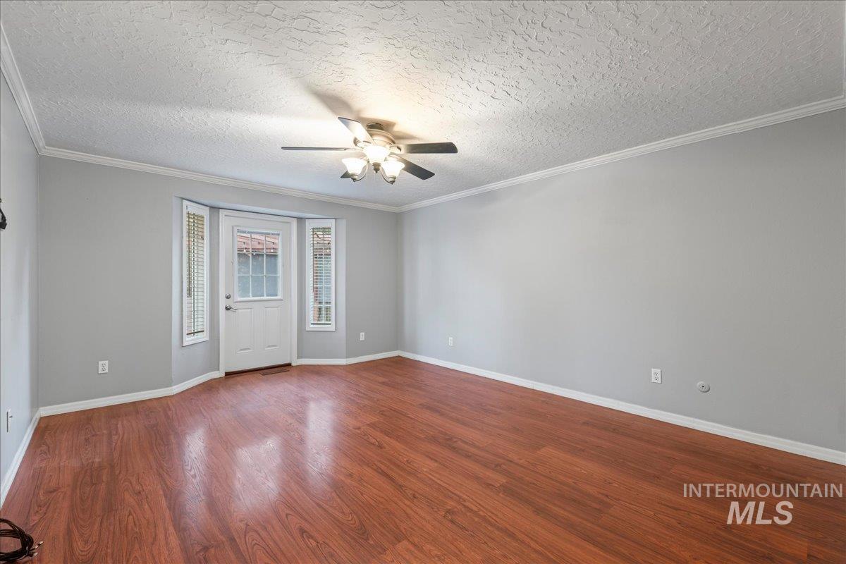 11457 Alejandro Street Boise, ID 83709 - Photo 18 of 42 Spare room with dark wood-style flooring, ceiling fan, a textured ceiling, and ornamental molding