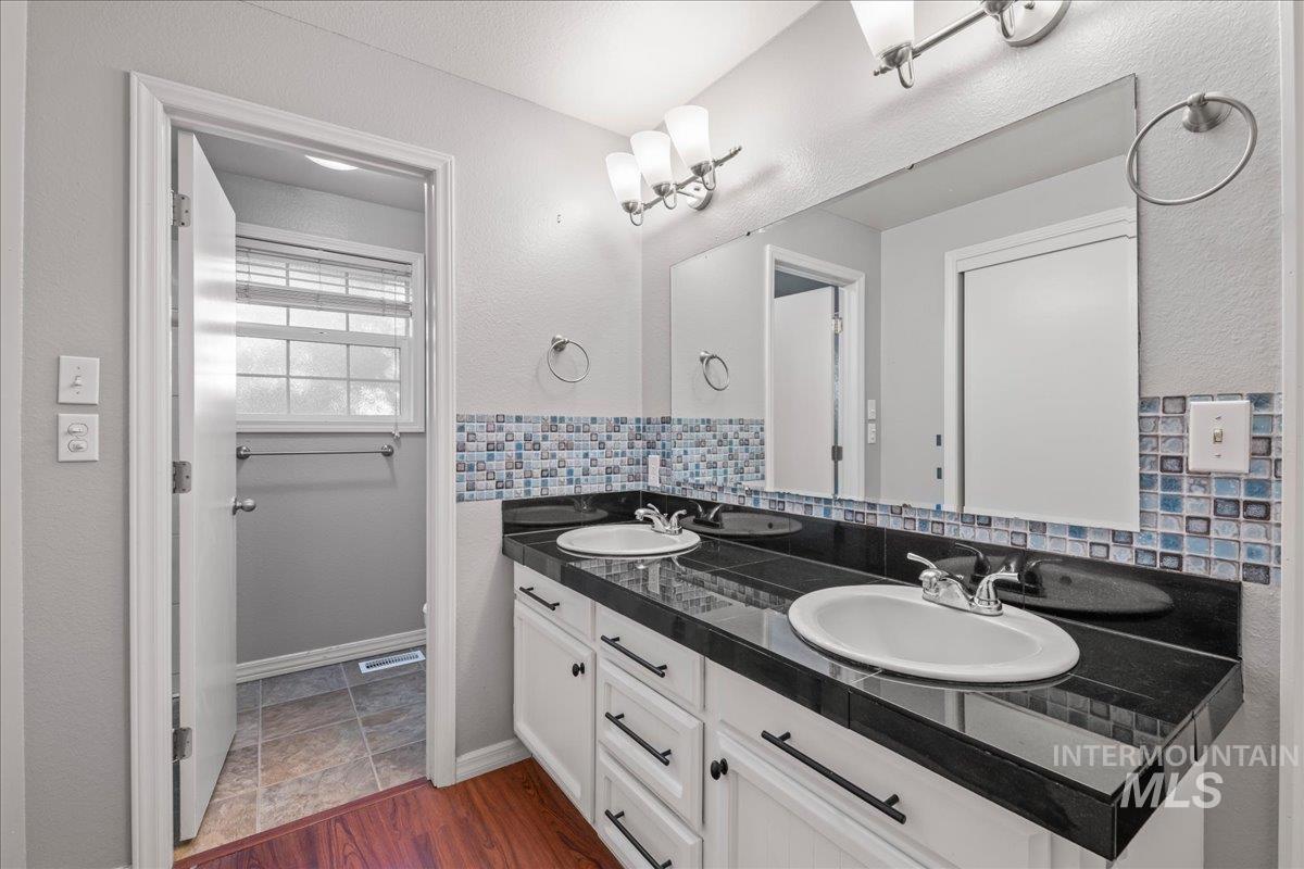 11457 Alejandro Street Boise, ID 83709 - Photo 20 of 42 Full bathroom featuring double vanity, a textured wall, and dark wood-style flooring