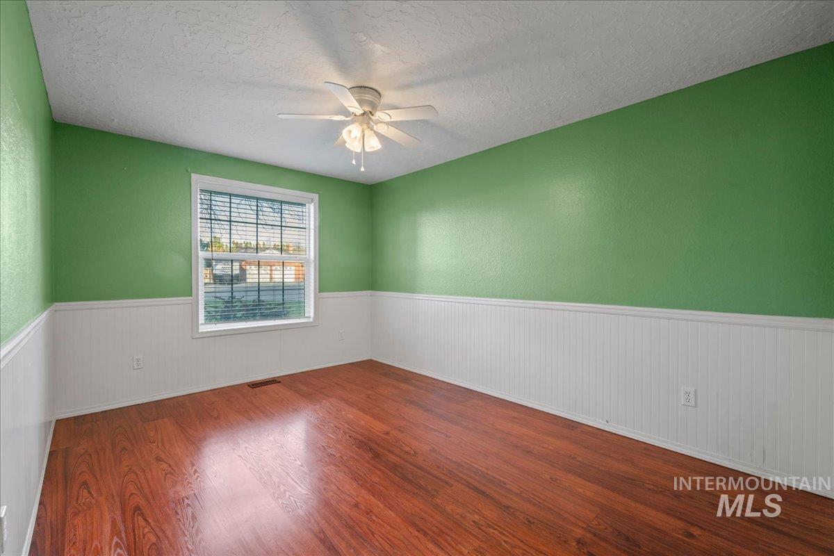 11457 Alejandro Street Boise, ID 83709 - Photo 23 of 42 Spare room with dark wood finished floors, a textured ceiling, wainscoting, and a ceiling fan
