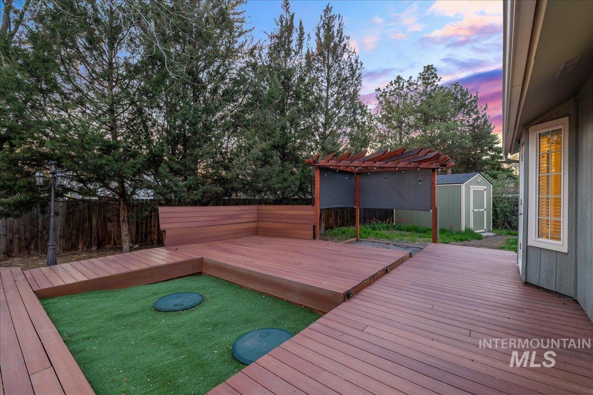 11457 Alejandro Street Boise, ID 83709 - Photo 28 of 42 Deck at dusk featuring a storage unit, a fenced backyard, and a pergola