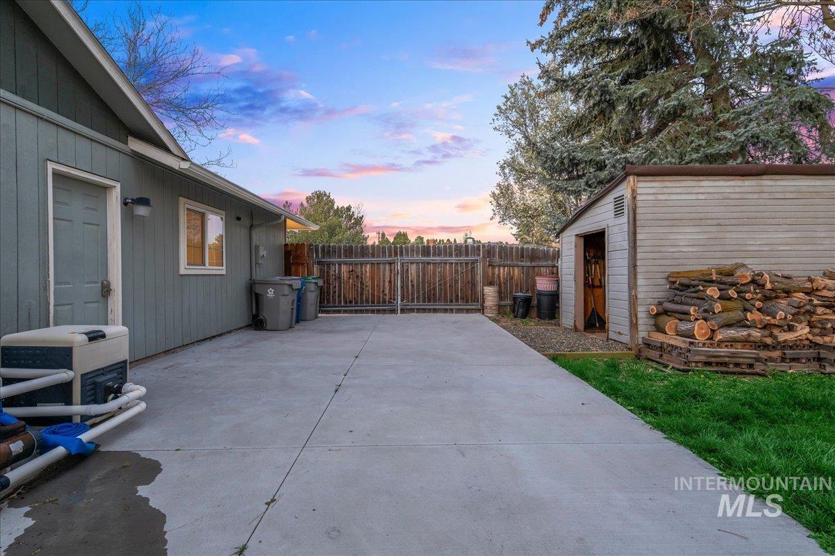 11457 Alejandro Street Boise, ID 83709 - Photo 34 of 42 Patio terrace at dusk featuring an outbuilding, a fenced backyard, and a patio area