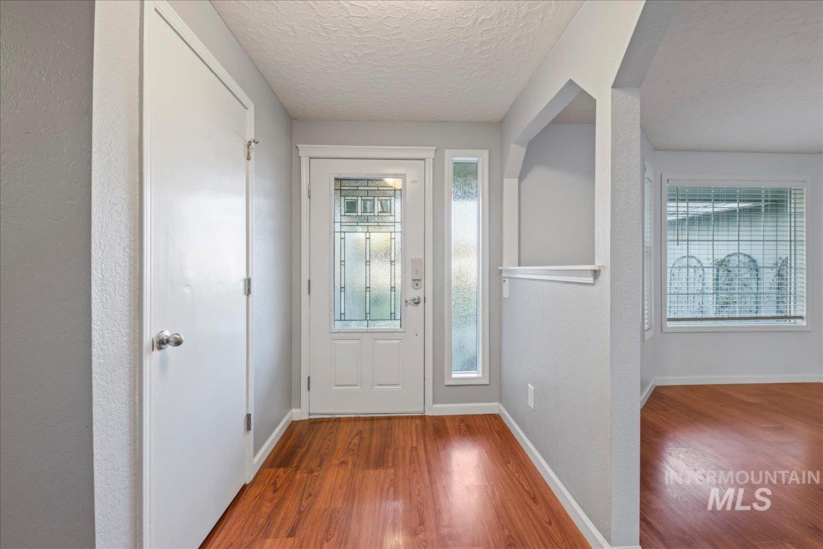 11457 Alejandro Street Boise, ID 83709 - Photo 4 of 42 Foyer entrance with wood finished floors, a textured ceiling, a textured wall, and plenty of natural light