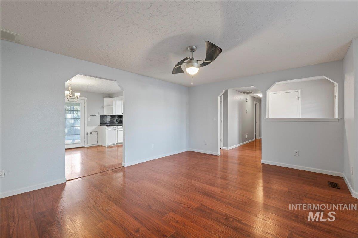 11457 Alejandro Street Boise, ID 83709 - Photo 6 of 42 Unfurnished room with arched walkways, a textured ceiling, a ceiling fan, and dark wood-type flooring