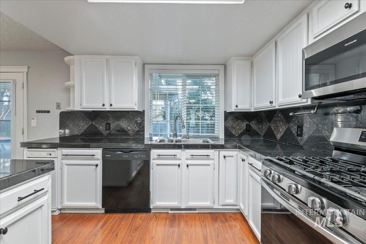 11457 Alejandro Street Boise, ID 83709 - Photo 9 of 42 Kitchen with stainless steel appliances, white cabinets, tile counters, and light wood-style flooring