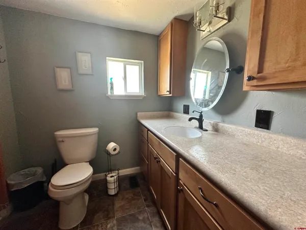 a bathroom with a granite countertop toilet sink and mirror