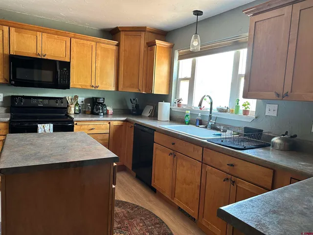 a kitchen with granite countertop a sink a stove top oven a granite counter space and cabinets