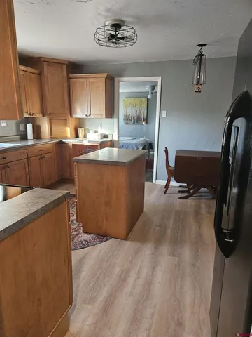 a kitchen with stainless steel appliances granite countertop a refrigerator a sink dishwasher a stove with wooden cabinets and floor