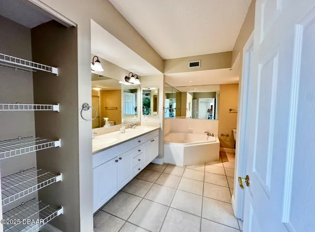 a spacious bathroom with a double vanity sink mirror and bathtub