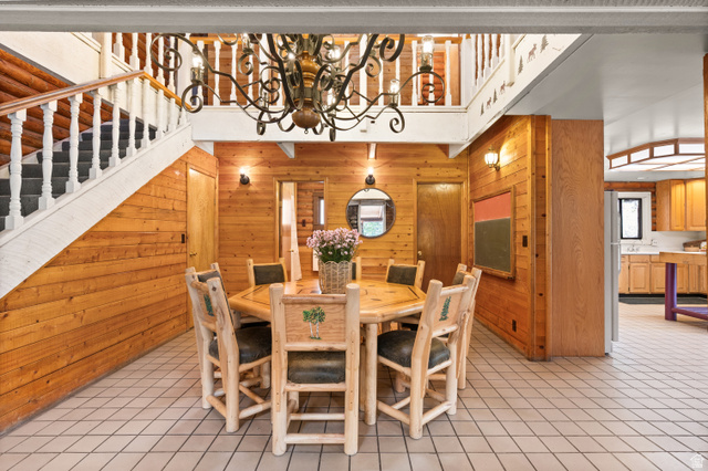 4725 Pine Ridge Road Evanston, UT 82930 - Photo 9 of 82 Spacious dining area featuring wood-paneled walls, tile flooring, and a decorative chandelier