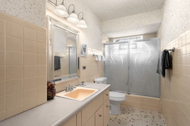 a bathroom with a granite countertop sink a toilet a mirror and shower
