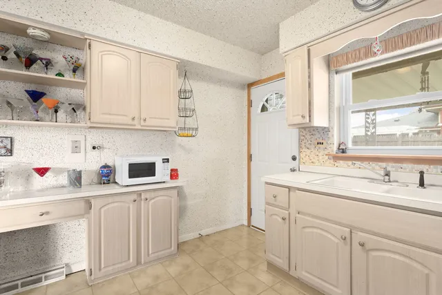 a kitchen with white cabinets a sink dishwasher and white stove next to a window