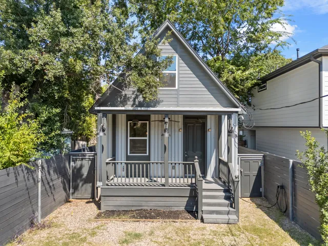 a view of small house with wooden deck and furniture