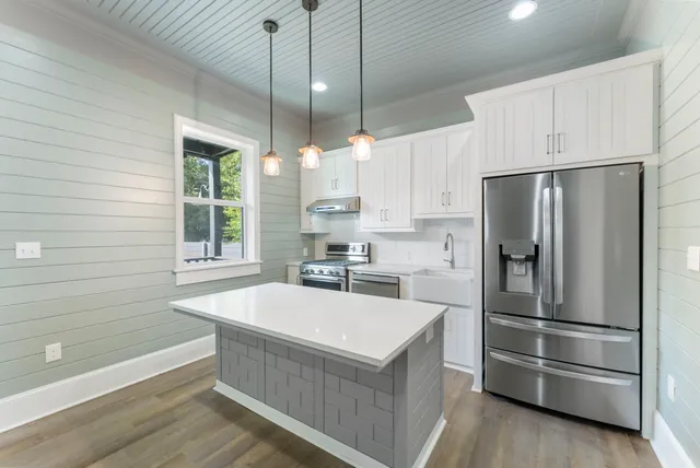a large white kitchen with a large window a refrigerator and a sink