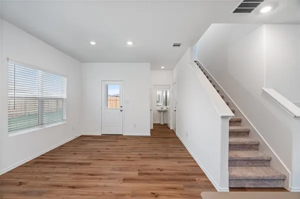 a view of a hallway with wooden floor and staircase