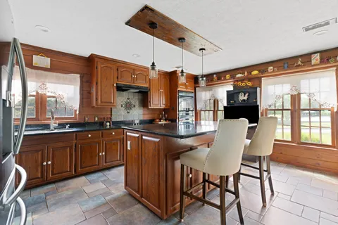 a kitchen with stainless steel appliances granite countertop a table chairs and a sink