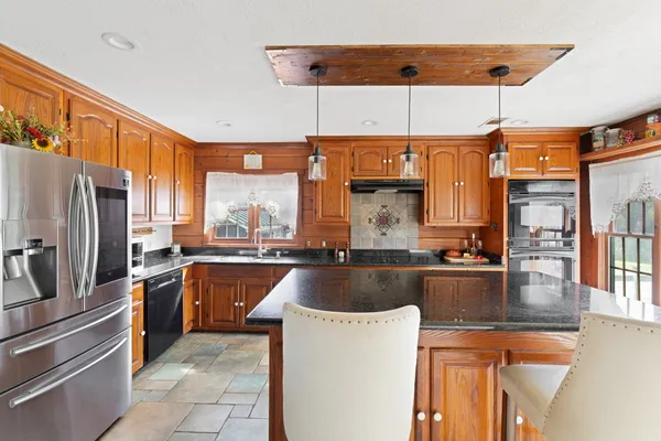 a kitchen with stainless steel appliances granite countertop a sink and a refrigerator