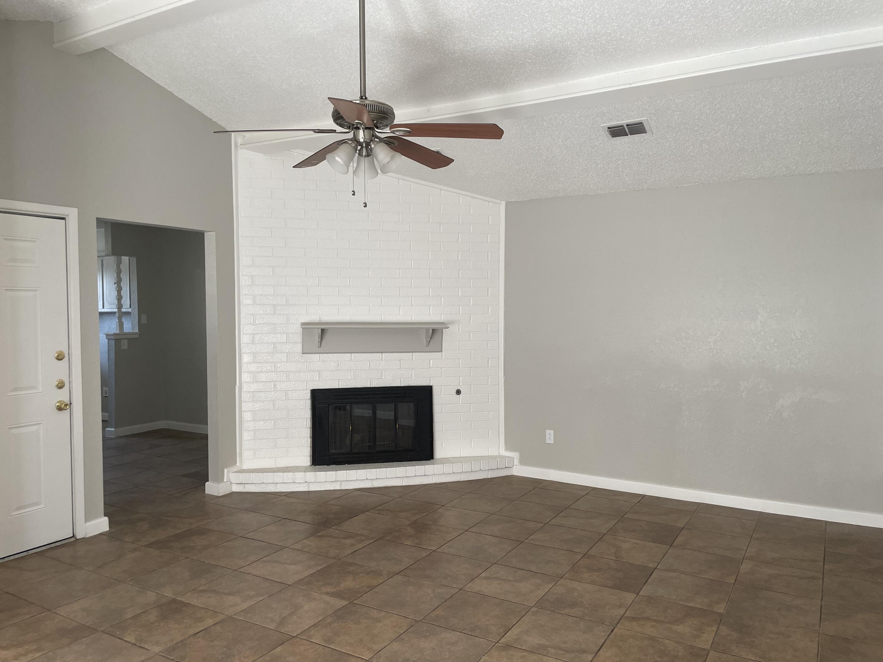 6917 Fremont Avenue Lubbock, TX 79413 - Photo 2 of 9 an empty room with a fireplace and a ceiling fan