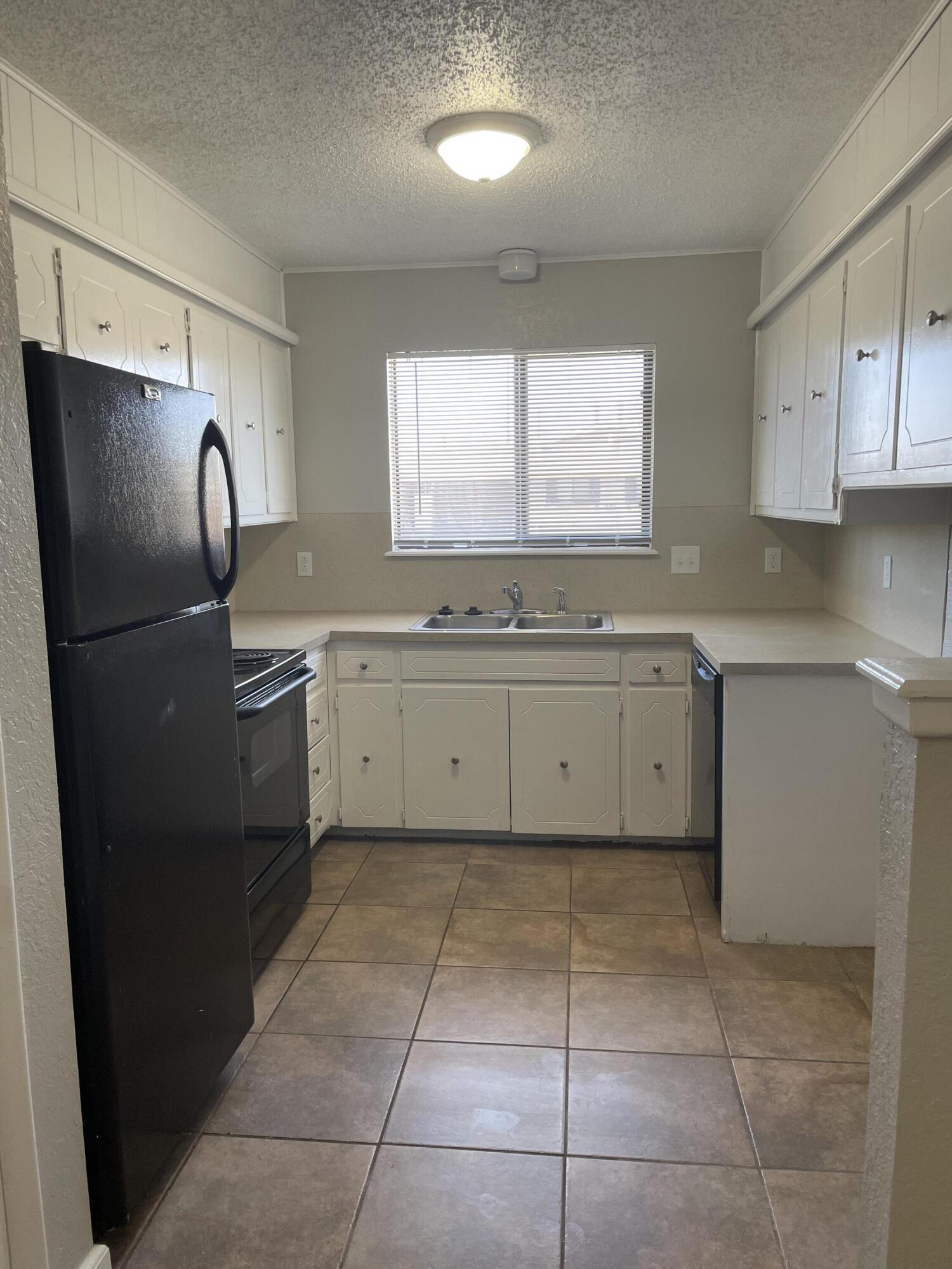 6917 Fremont Avenue Lubbock, TX 79413 - Photo 4 of 9 a kitchen with a sink a refrigerator and cabinets