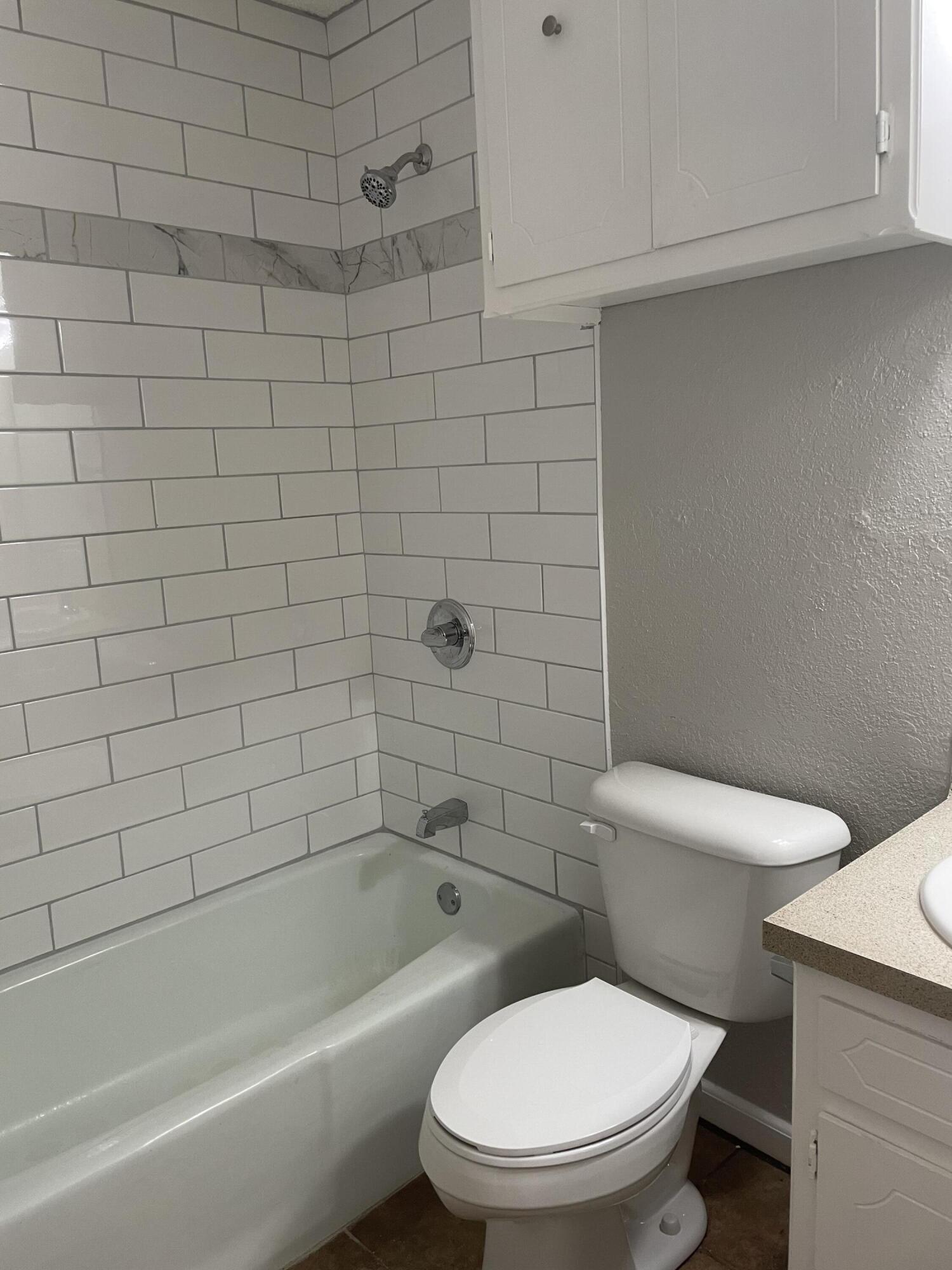 6917 Fremont Avenue Lubbock, TX 79413 - Photo 6 of 9 a white toilet and tub sitting next to a bathroom sink