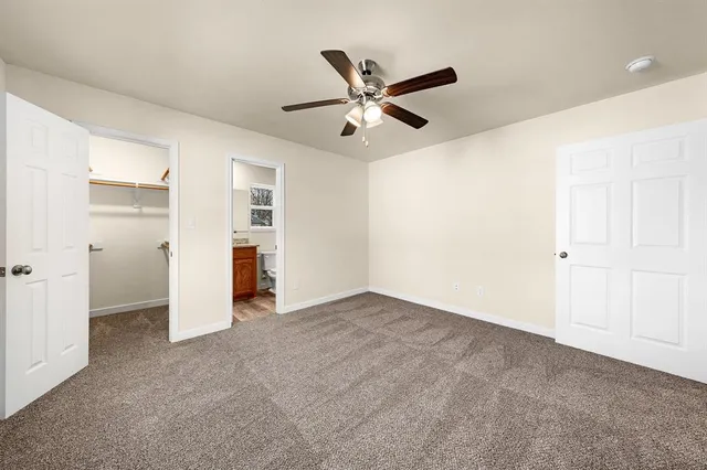 an empty room with closet and a ceiling fan