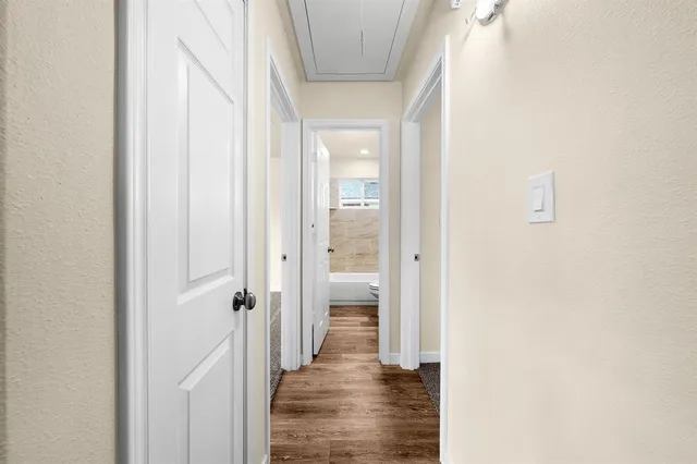 a view of a hallway with wooden floor and a bathroom