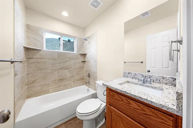 a bathroom with a granite countertop sink toilet mirror and bathtub