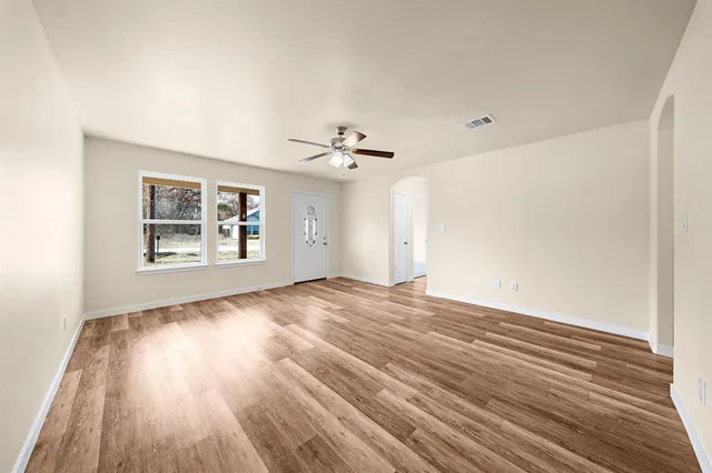 a view of an empty room with wooden floor and a window
