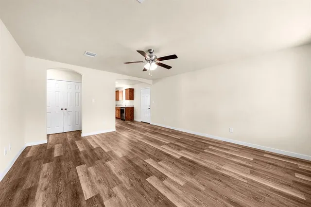 a view of empty room with wooden floor and ceiling fan