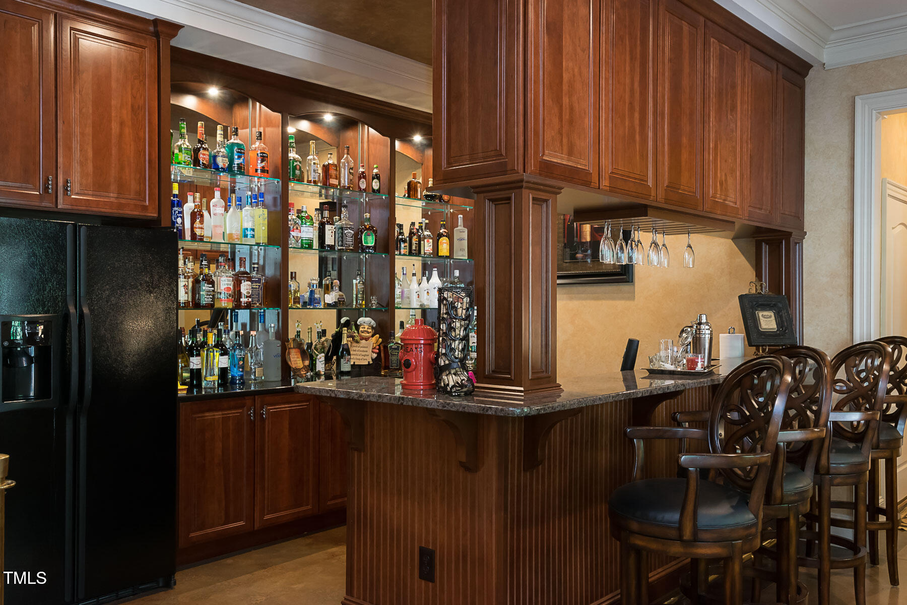 11201 Jonas Ridge Lane Raleigh, NC 27613 - Photo 62 of 79 • Restaurant-style bar (2nd kitchen) featuring glass shelving, cherry-stained cabinets, upgraded granite countertops, pull out shelves, designer hardware, and a built-in sink, refrigerator, dishwasher, and wine rack.