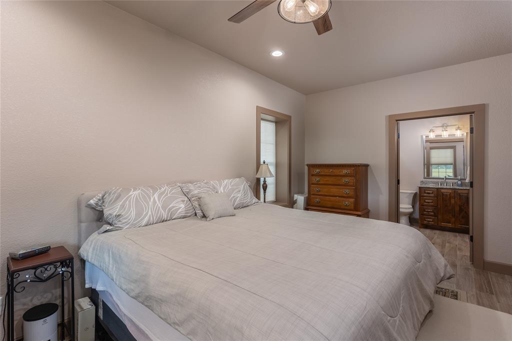 210 Spring Branch Trail North Springtown, TX 76082 - Photo 14 of 36 a bedroom with a large bed and a chandelier