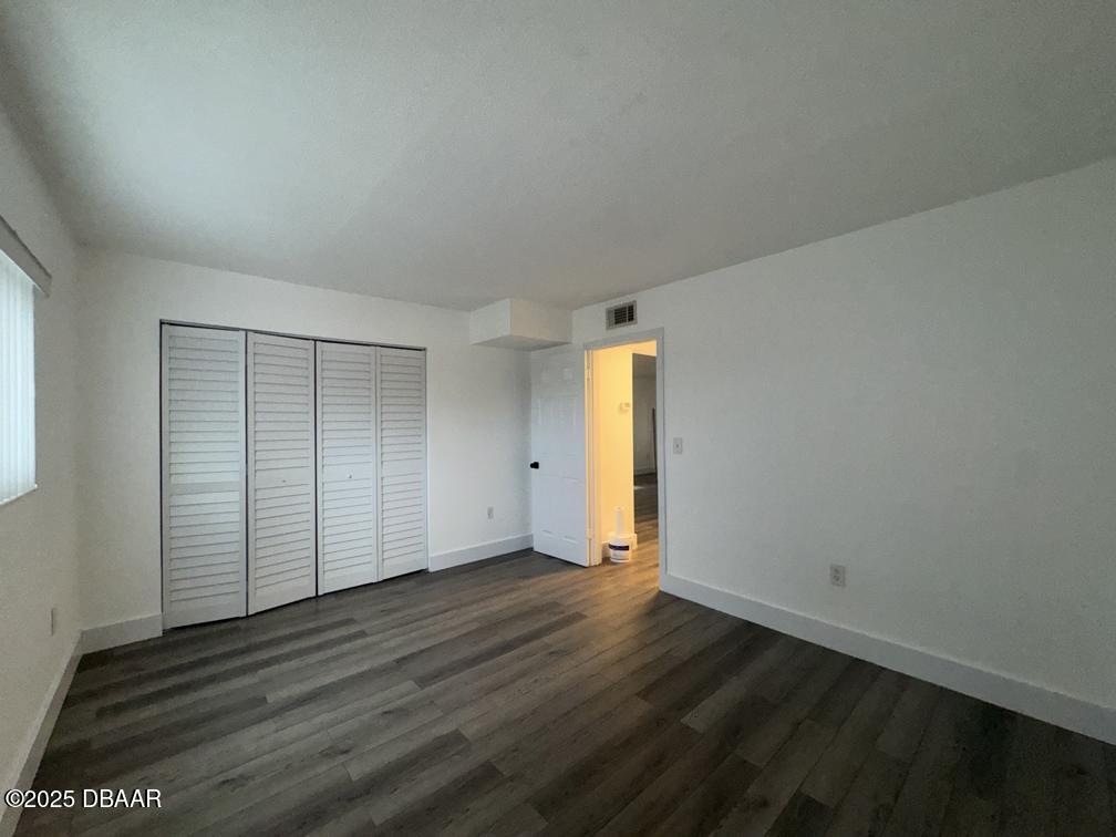 2711 North Halifax Avenue, Unit 385 Daytona Beach, FL 32118 - Photo 12 of 18 an empty room with wooden floor and door
