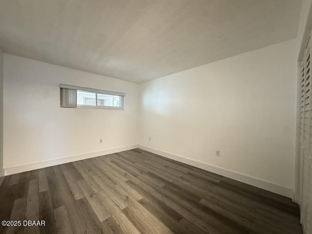 2711 North Halifax Avenue, Unit 385 Daytona Beach, FL 32118 - Photo 8 of 18 a view of an empty room with wooden floor and a window