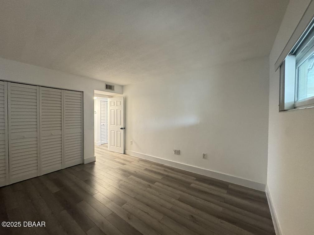 2711 North Halifax Avenue, Unit 385 Daytona Beach, FL 32118 - Photo 9 of 18 an empty room with wooden floor and windows